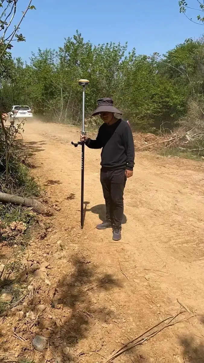 造价人员手持 RTK 接收机在施工场地进行外业查勘放样